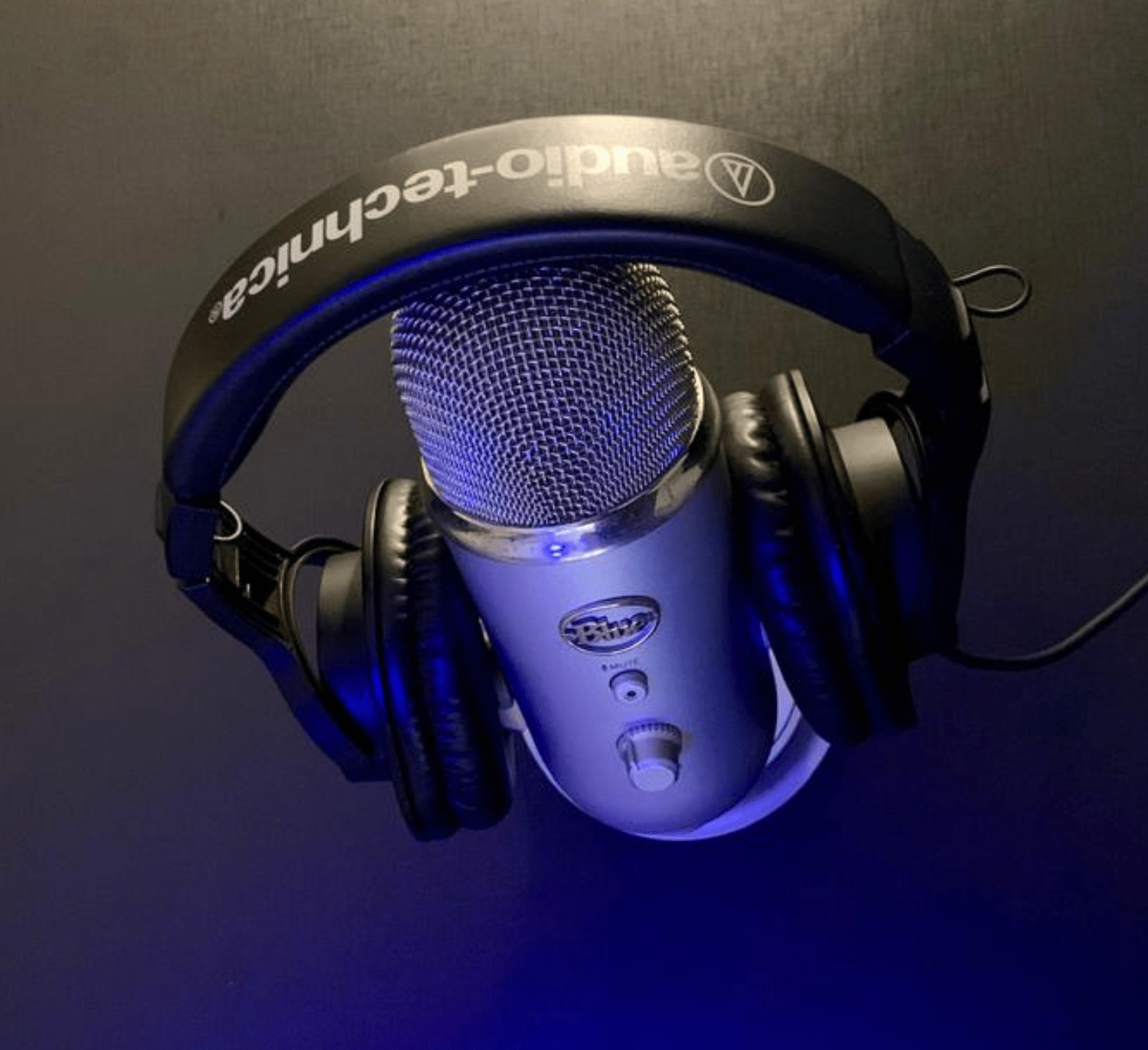 imagem de um microfone blue yeti prata com um fone de ouvido audio-technica